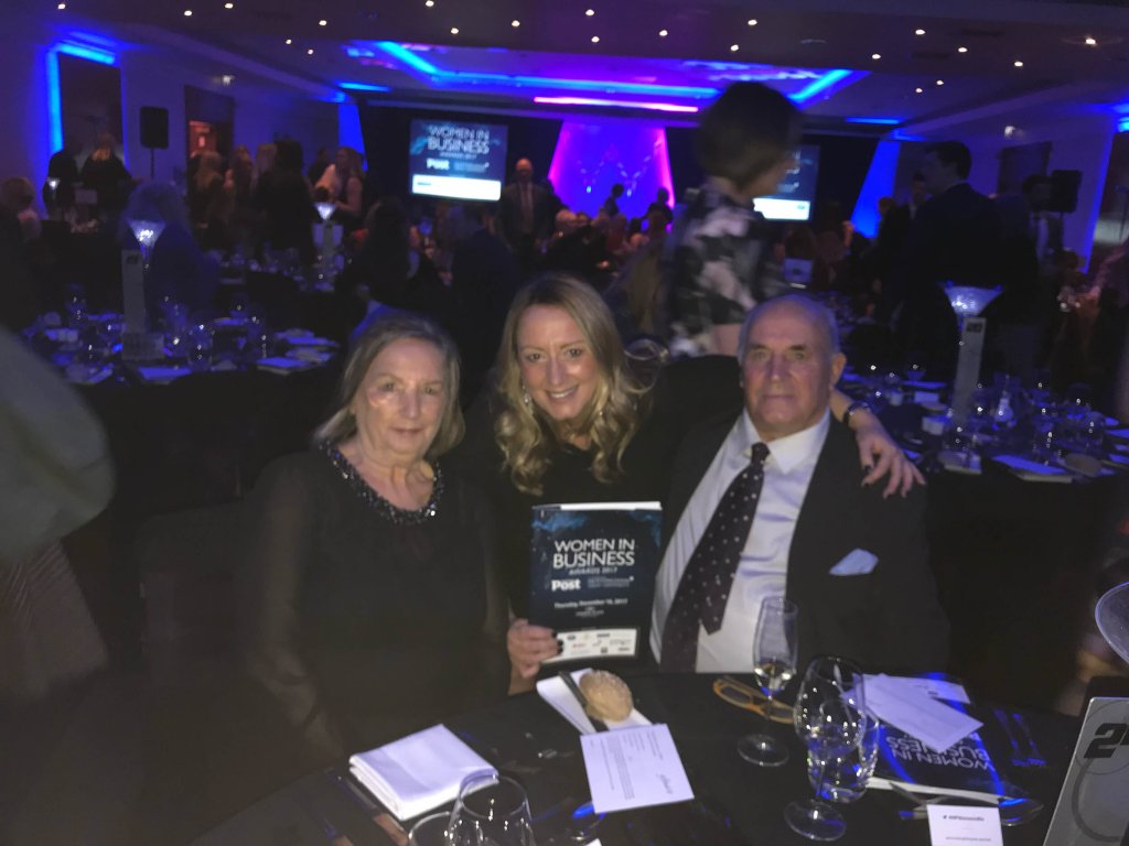 2 women and a man are sitting at a table at the Women in Business awards. They are all dressed in smart clothing.
