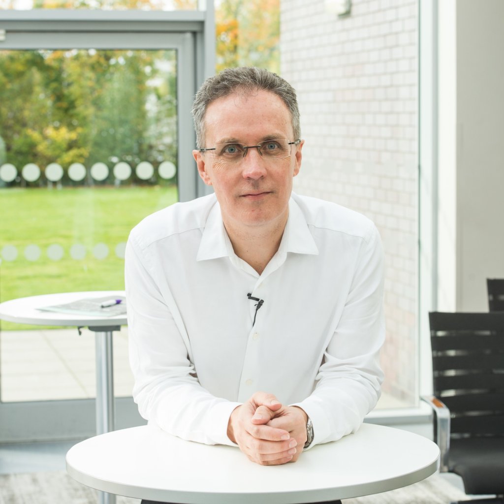 A business coach is sitting at a table in a modern corporate space.